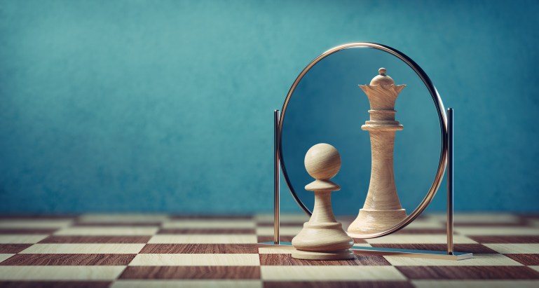 Illustrasjonen viser et sjakkbrett med en bonde som ser en dronning når den ser seg selv i speilet.